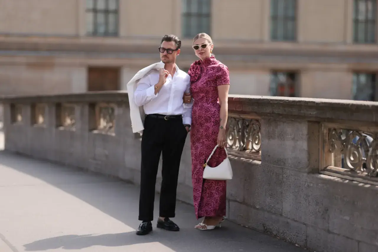 Elegancka para, inspiracja, jak się ubrać do teatru. On w białej koszuli i czarnych spodniach, ona w różowej sukni z kwiatowym wzorem.