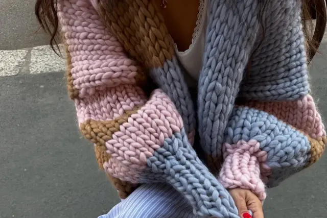 Gruby, kolorowy sweter robiony na drutach w odcieniach różu, brązu i błękitu. Zastanawiasz się, ile kosztuje sweter robiony na drutach?